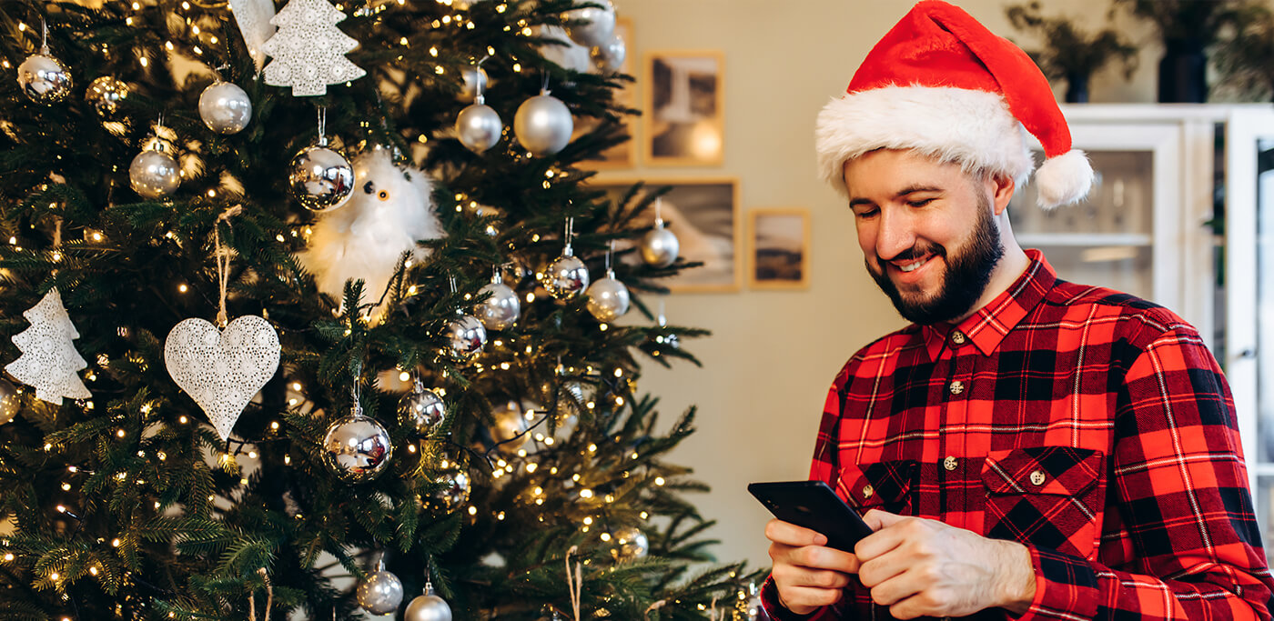 Man reading phone in front of Christmas tree