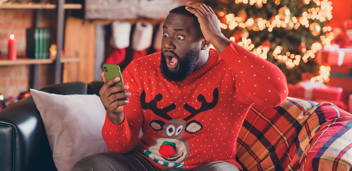 Excited man reading mobile in Christmas jumper