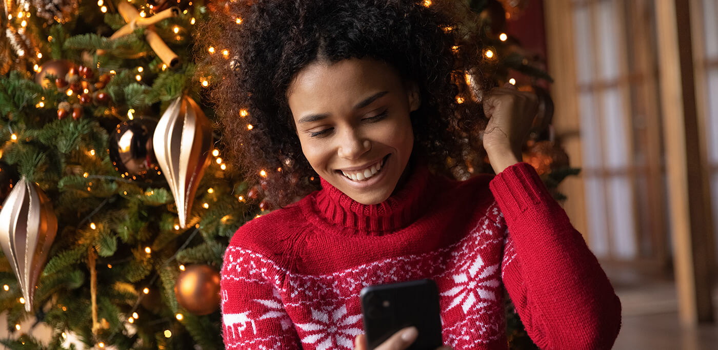 Women reading phone in front of Christmas tree