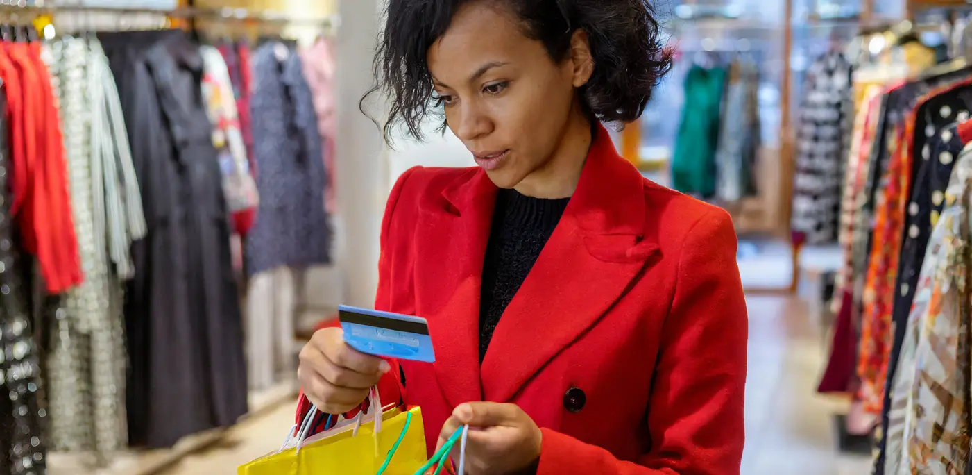 Young women in red coat buying clothes on her credit card