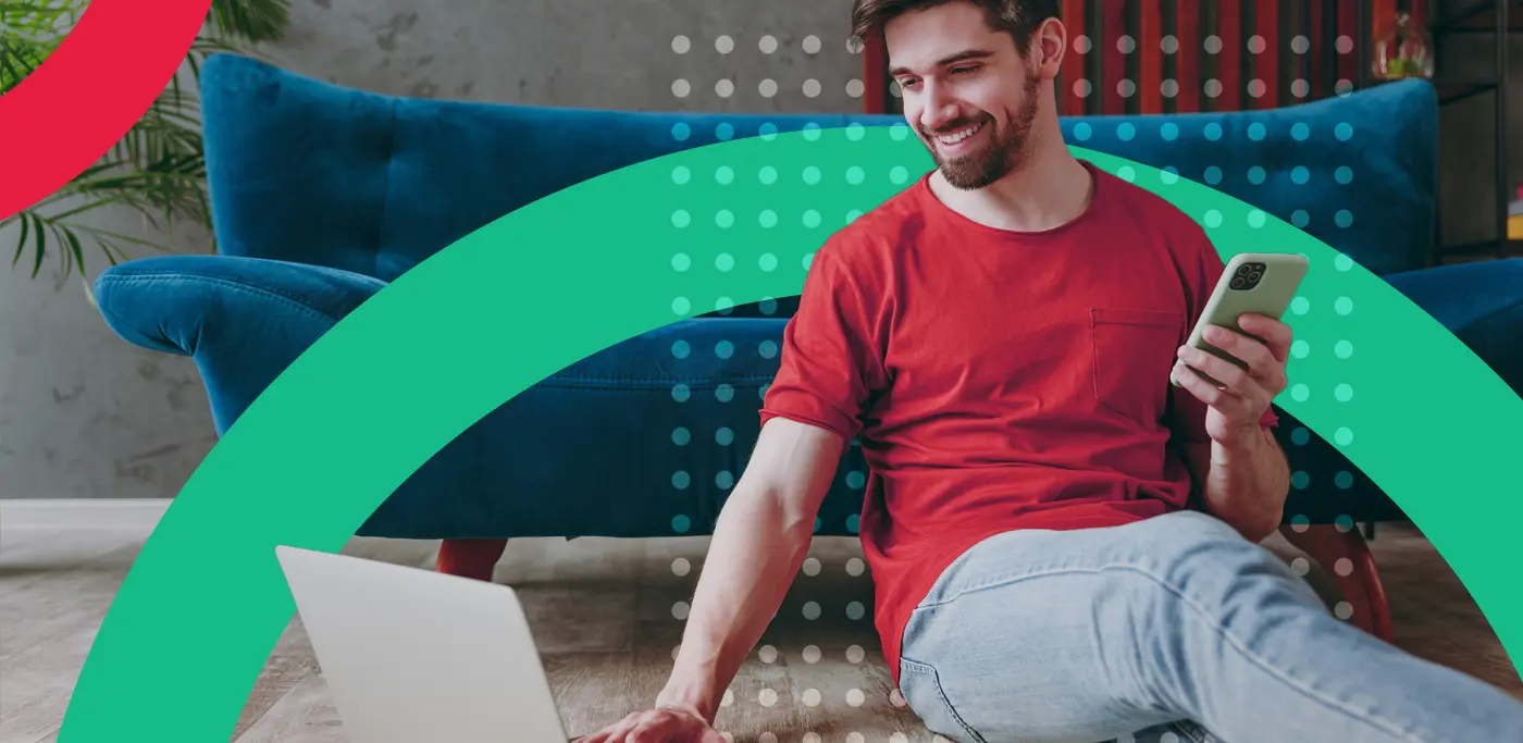 man on laptop and phone in front of a blue sofa