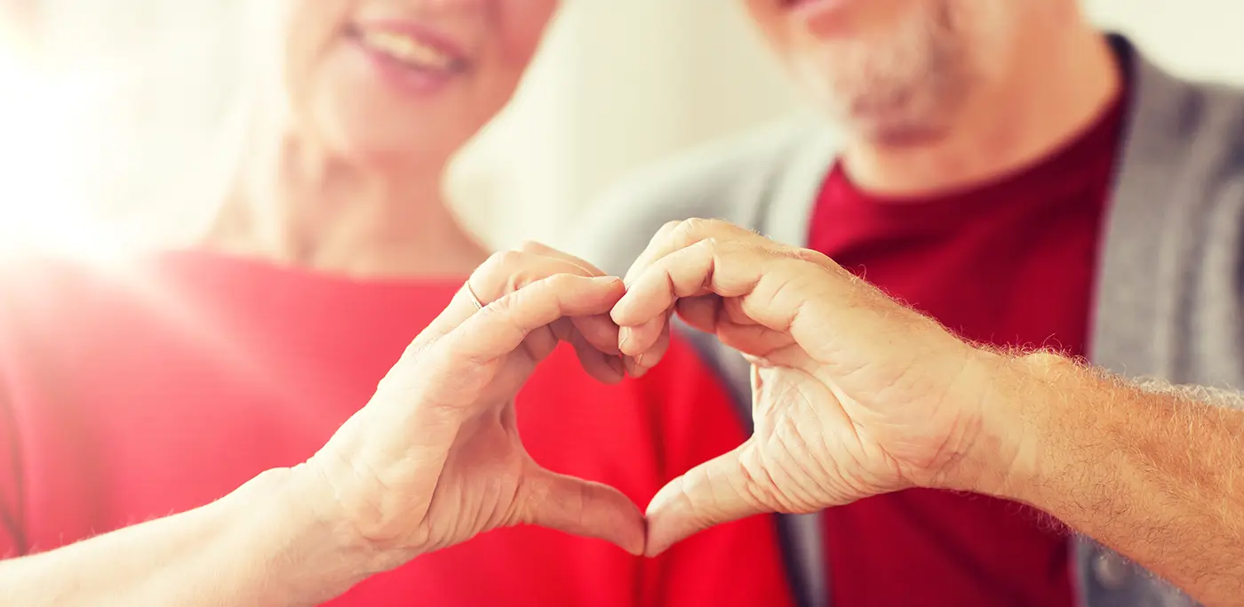 Older couple making a heart guesture with their hands