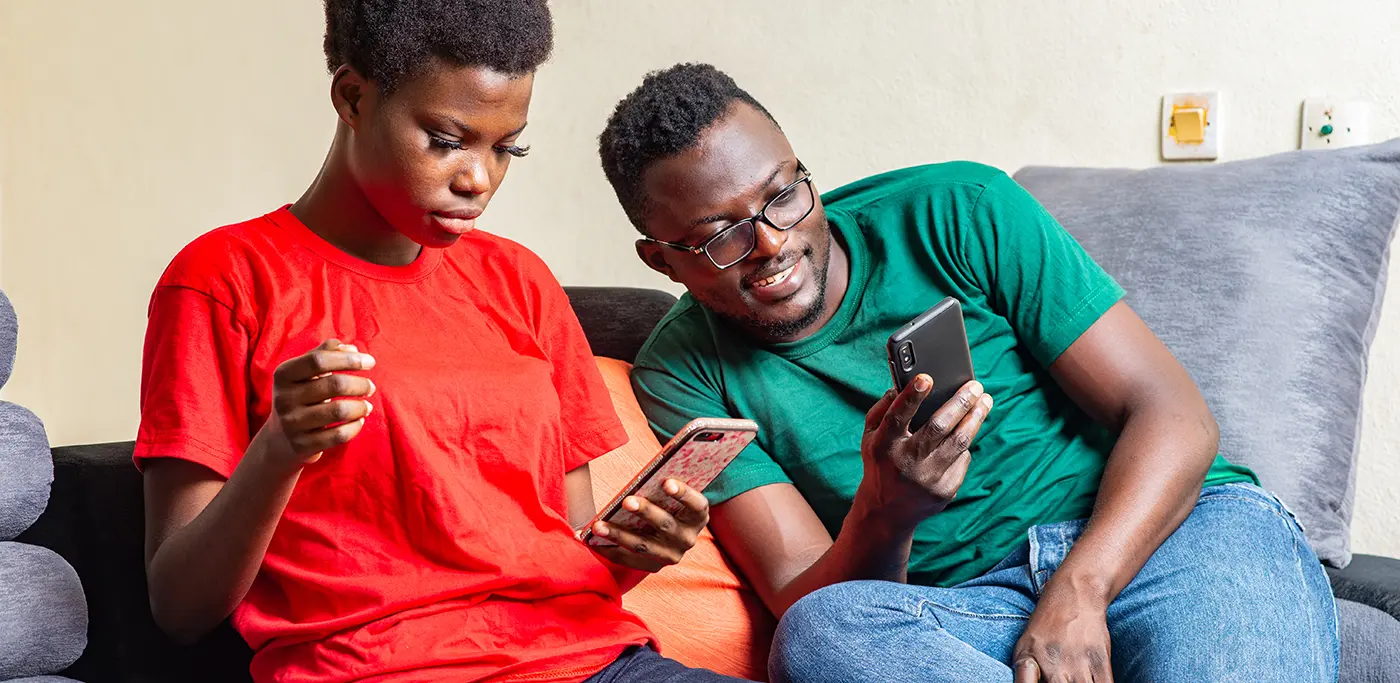 Black couple on the sofa browsing their mobile phones