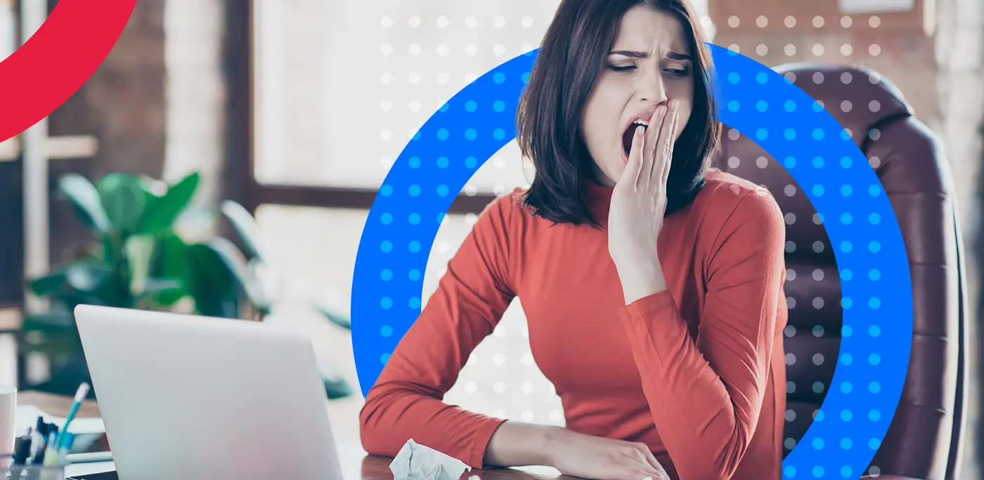 Youn women in red yawning as she is looking away from her laptop