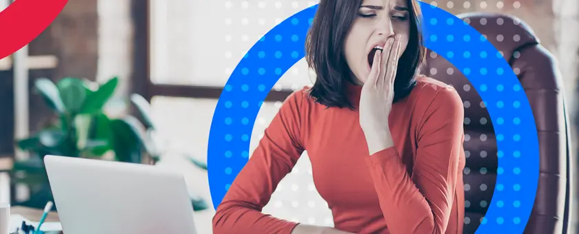 Youn women in red yawning as she is looking away from her laptop