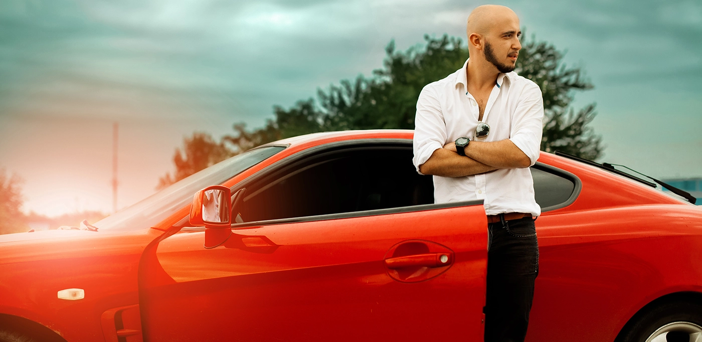 Man stood outside his red sports car