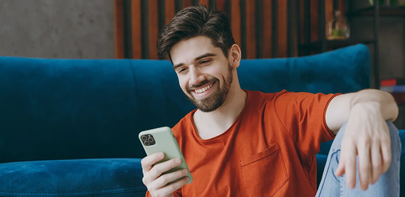 Man in red shirt browsing his mobile phone whilst sat down