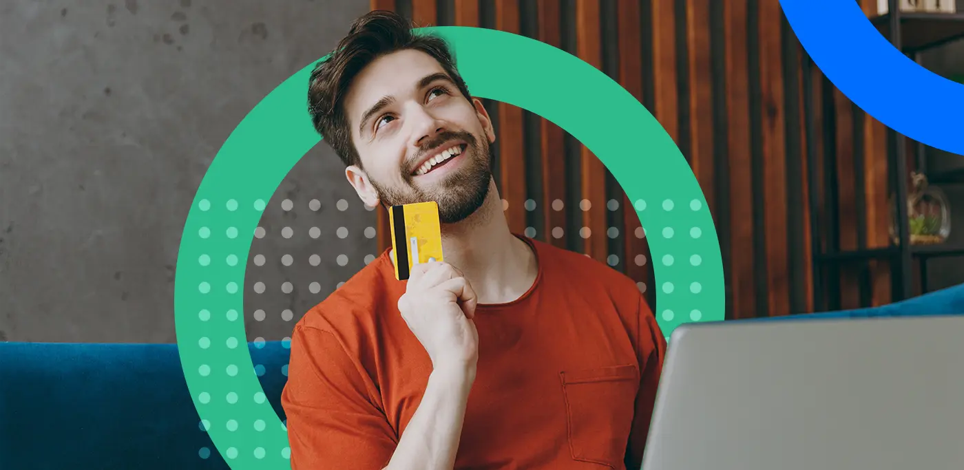 Man in red sitting in front of laptop with a credit card