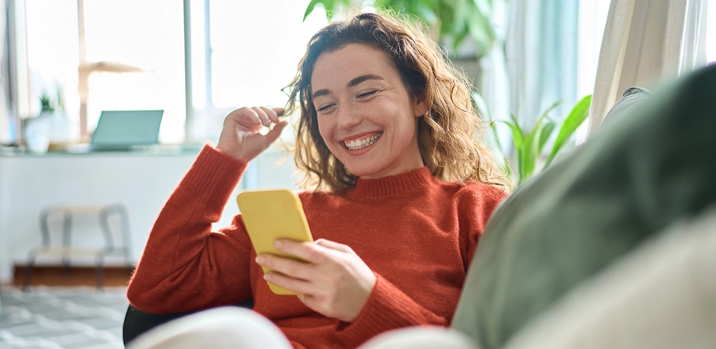 Women on sofa smiling at her mobile phone