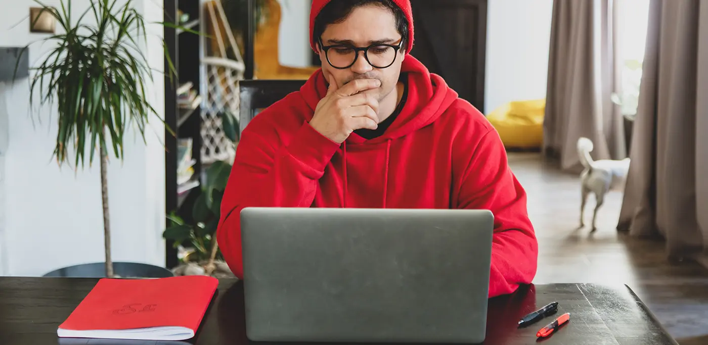 Man wearing red hoodie looking at his laptop