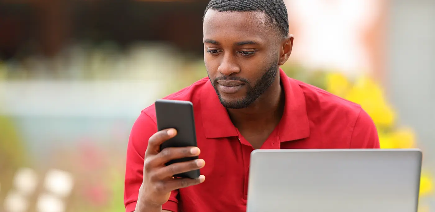 Man outside on park bench looking at mobile