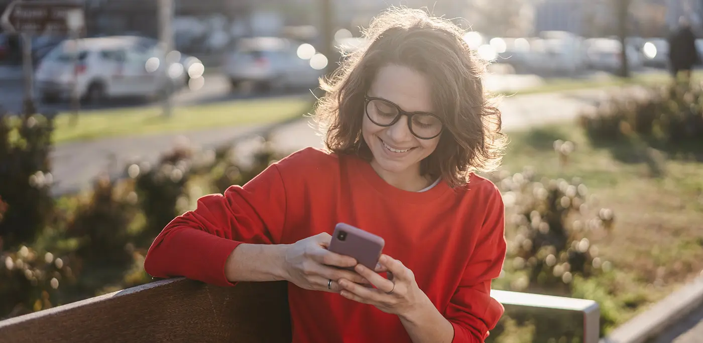 Women smiling at phone on park bench