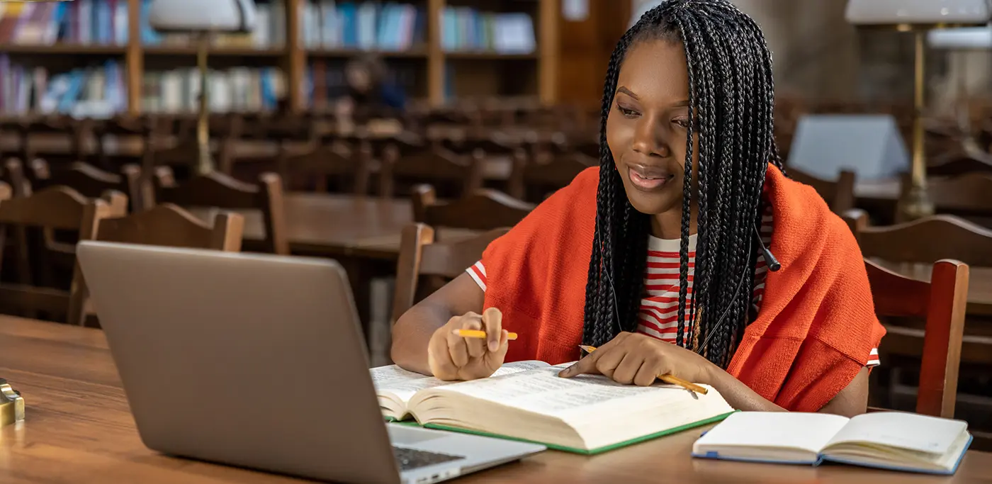 Black student working on laptop in the library