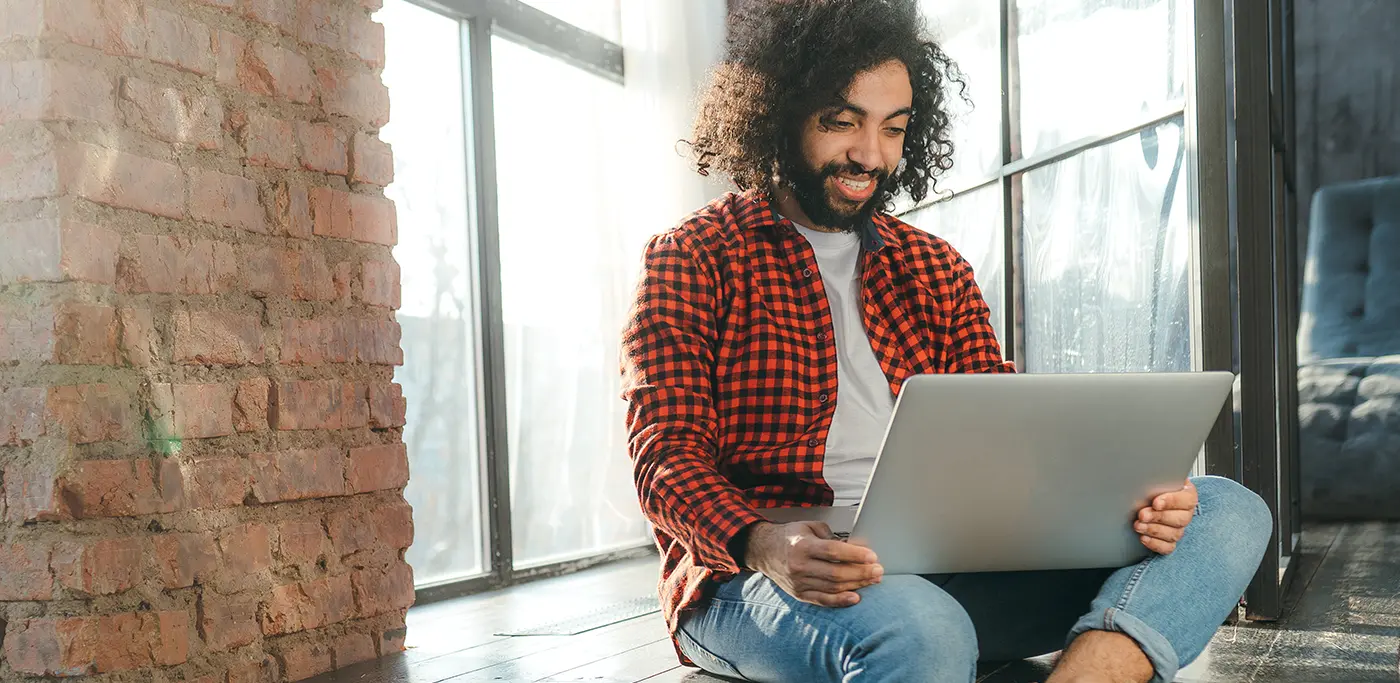 Male sat on top of counter with laptop on his lap