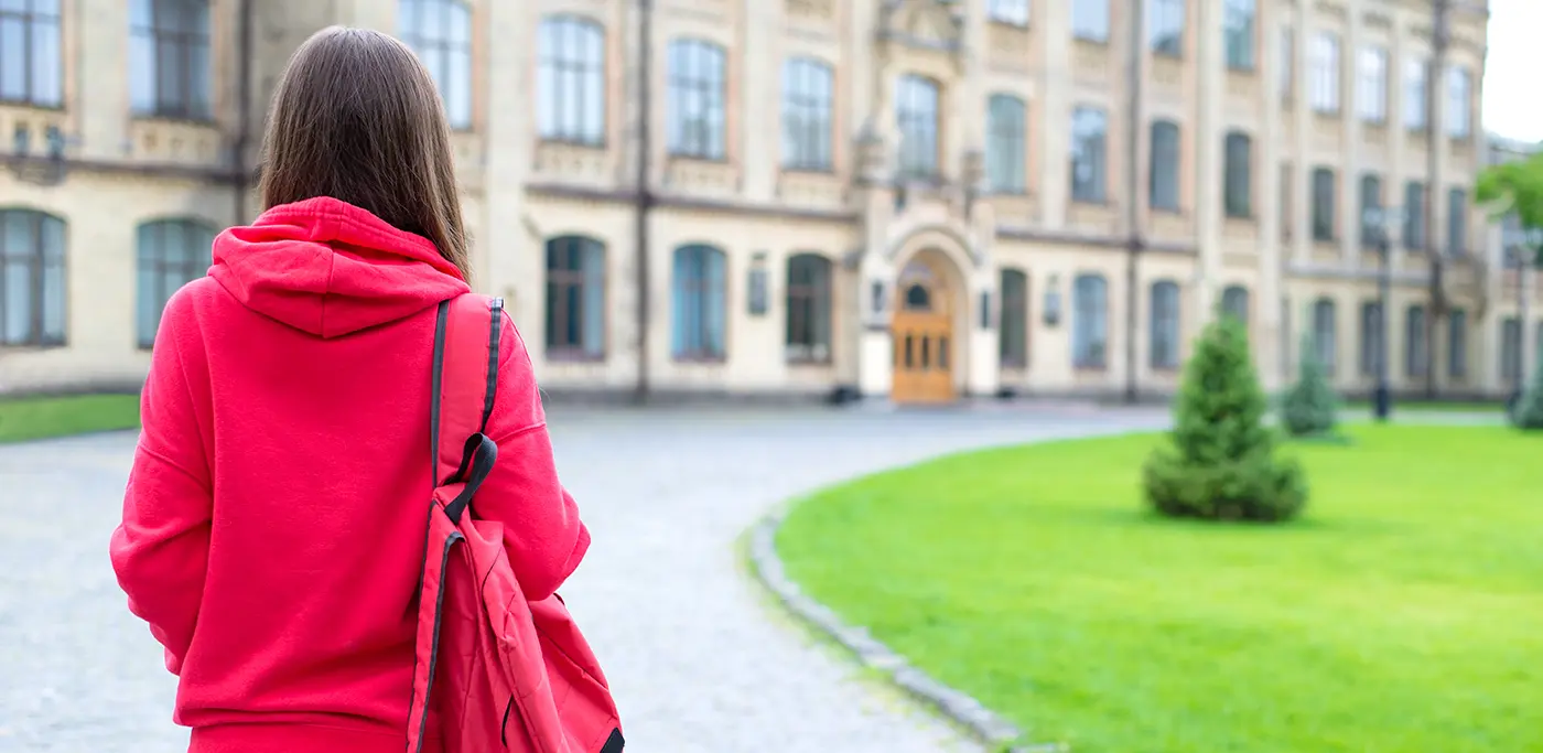 Student all in red walking towards an old uni building