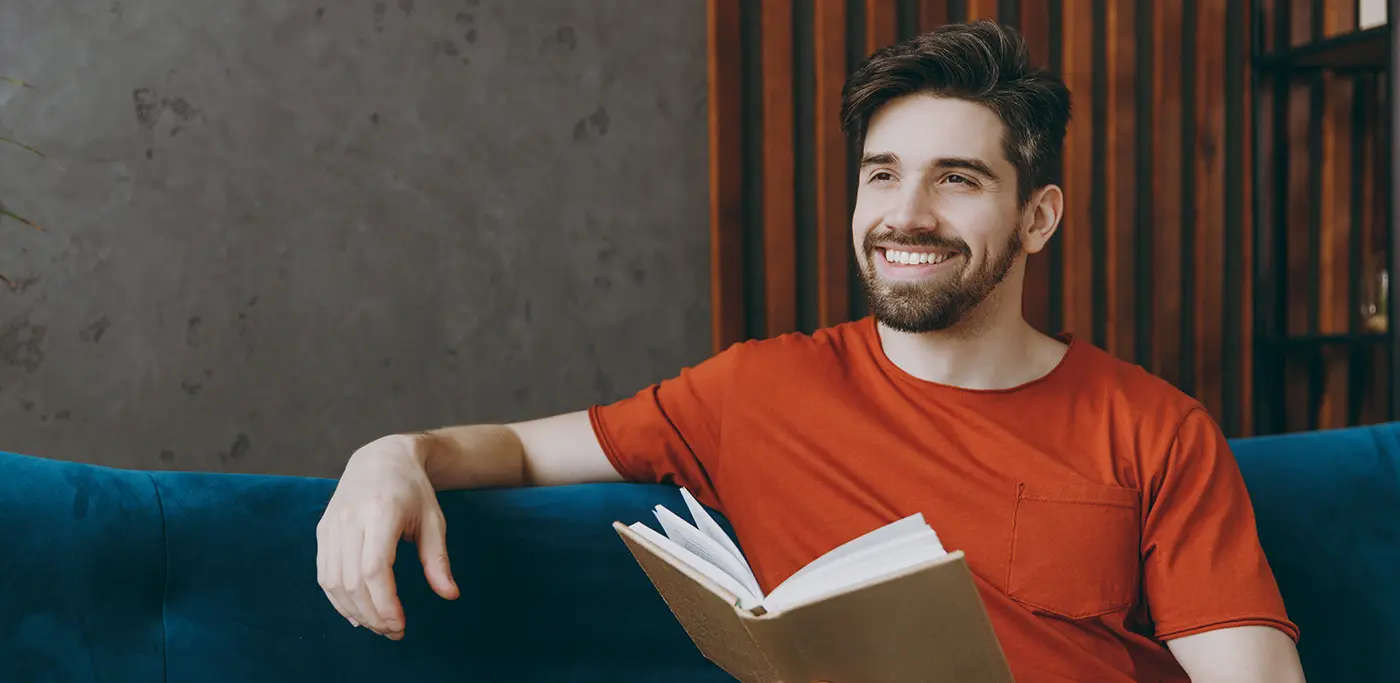 Student male reading book on a blue sofa