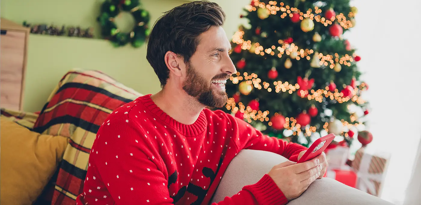 Man in red christmas jumper reading emails on his mobile