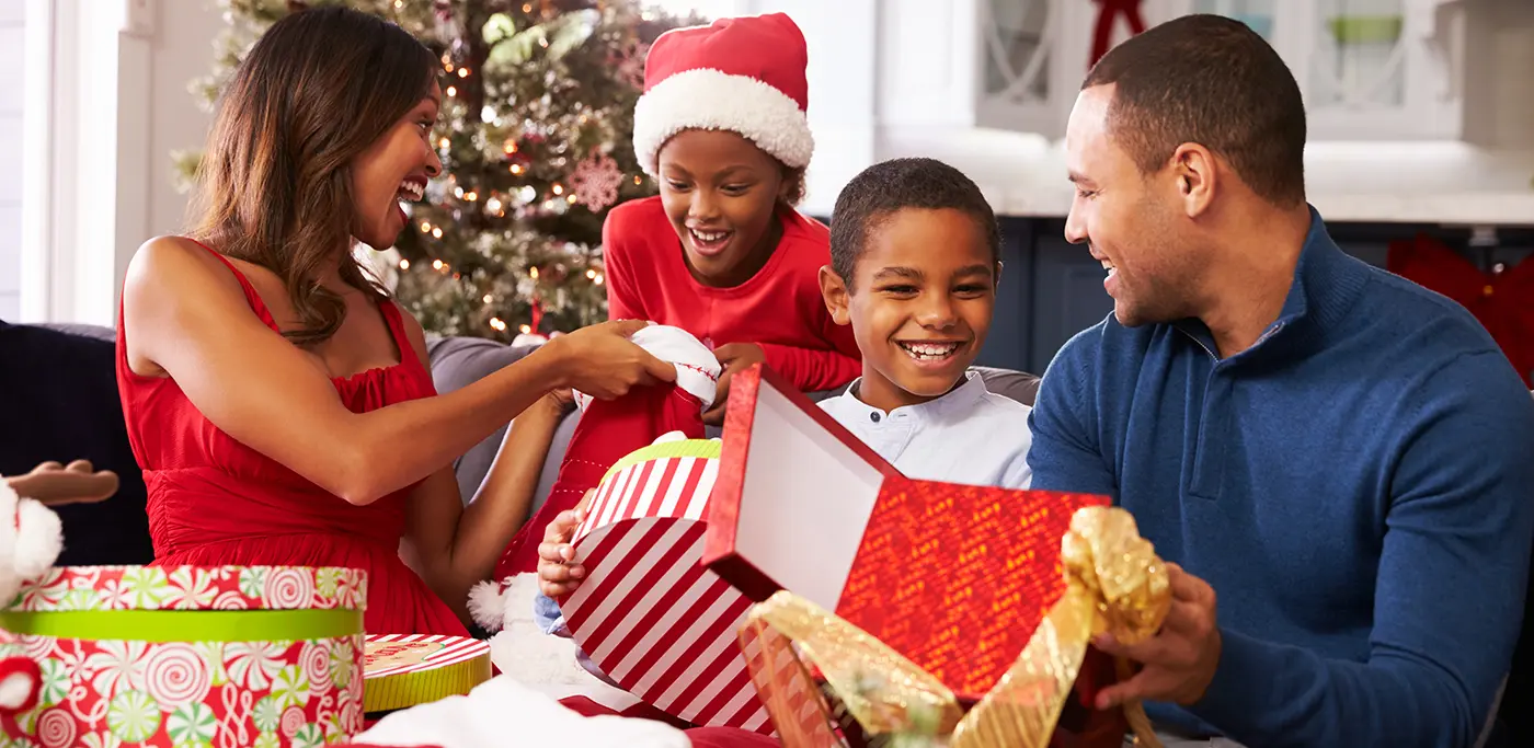 Family opening Christmas presents around the tree