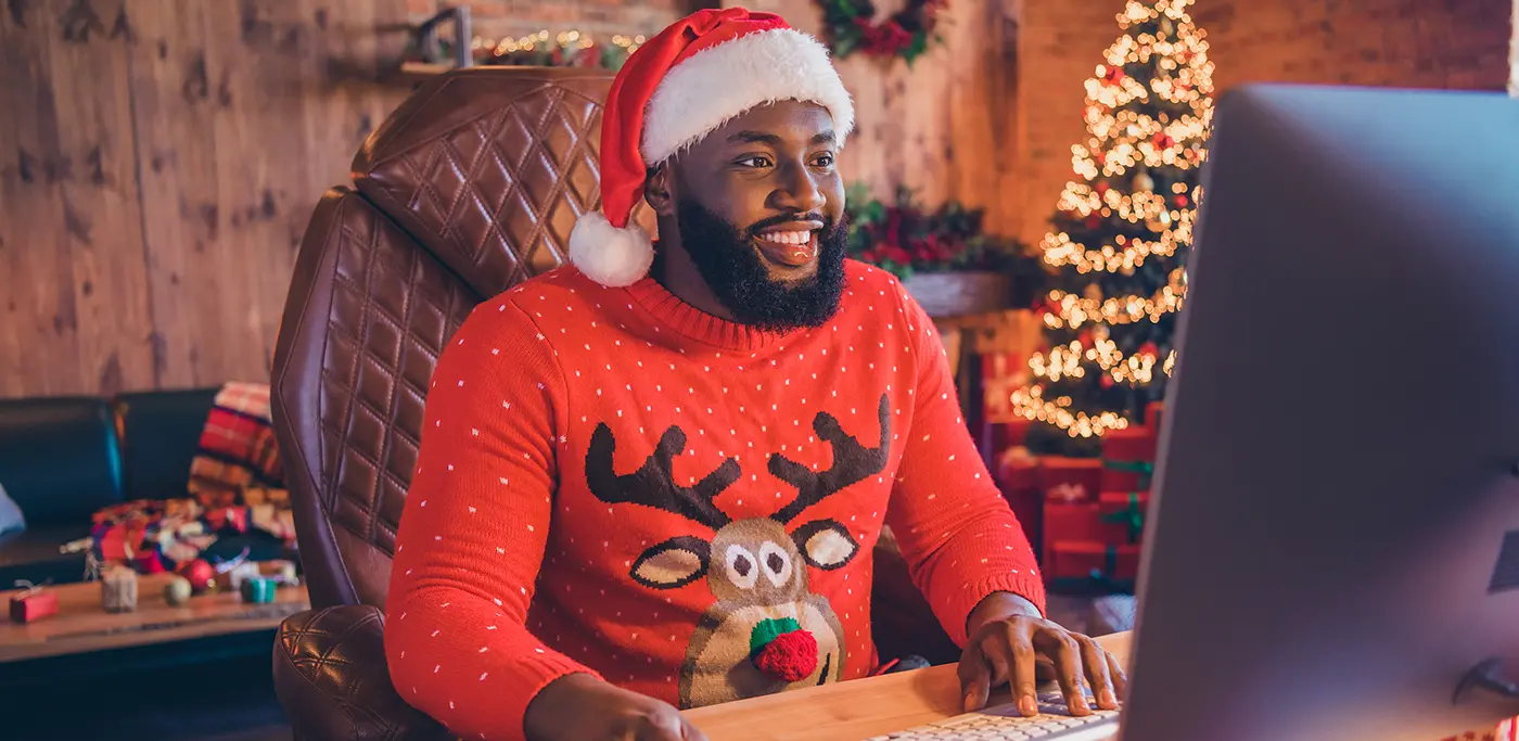 Happy man in Christmas jumper working on computer