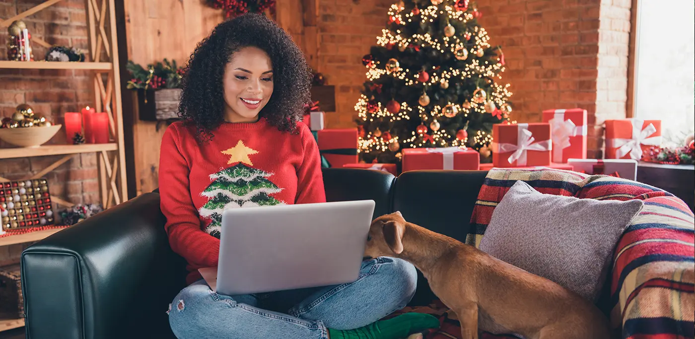 Women shopping online for gifts with her dog sat on sofa